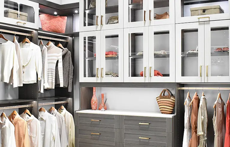 Walk in two toned grey and white closet with some glass doors and led lights